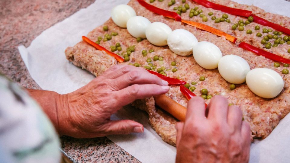 Na připravený plát masa klademe vejce, papriku, hrášek, párky a opatrně zabalíme